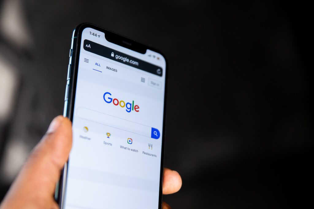 Hand holding a smartphone that features the Google search screen.